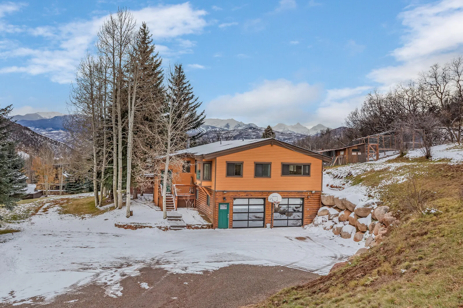 The guest house in winter, snow on the ground and peaks behind