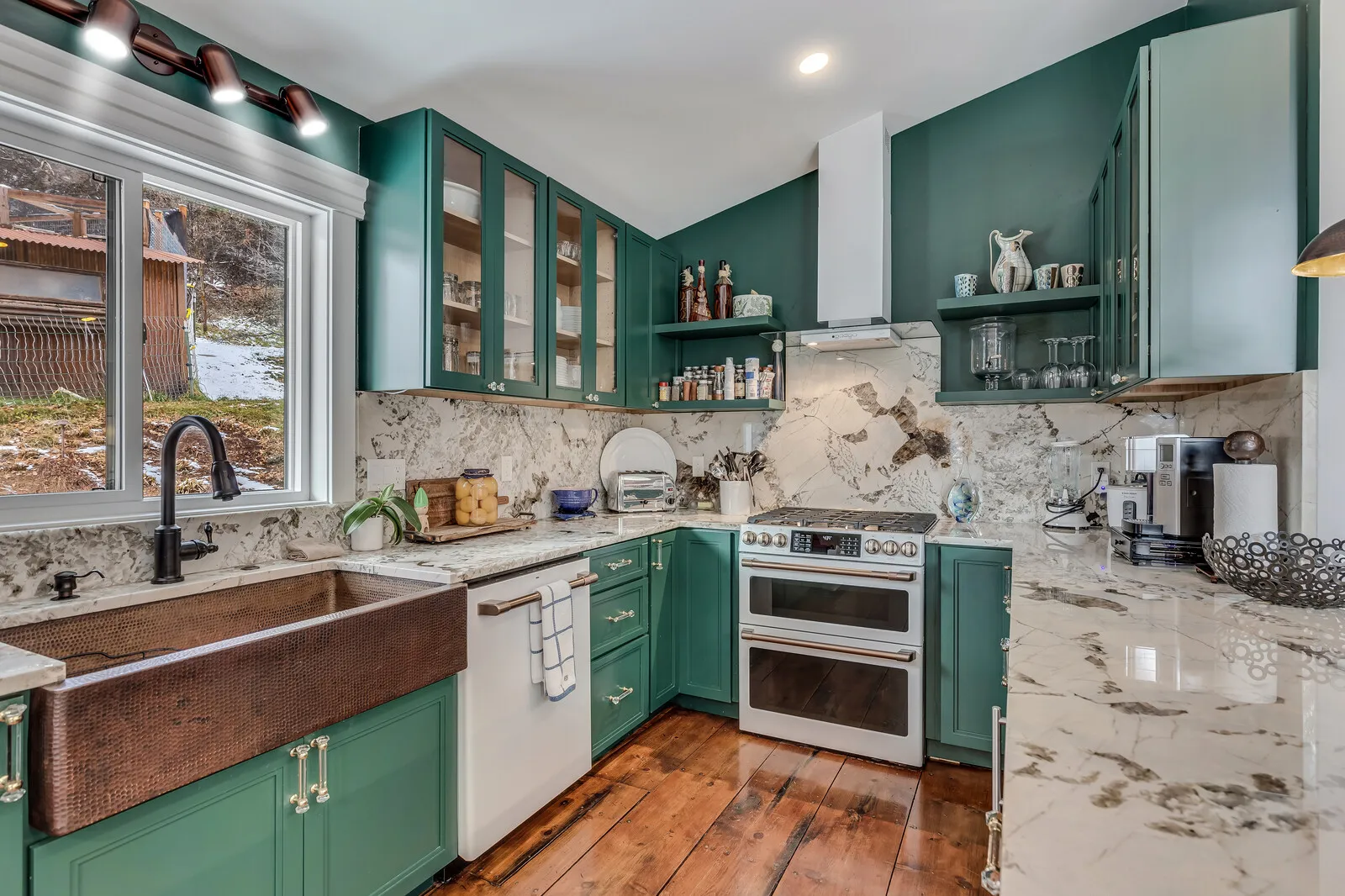 The kitchen: green cabinets, copper sink and a stone island